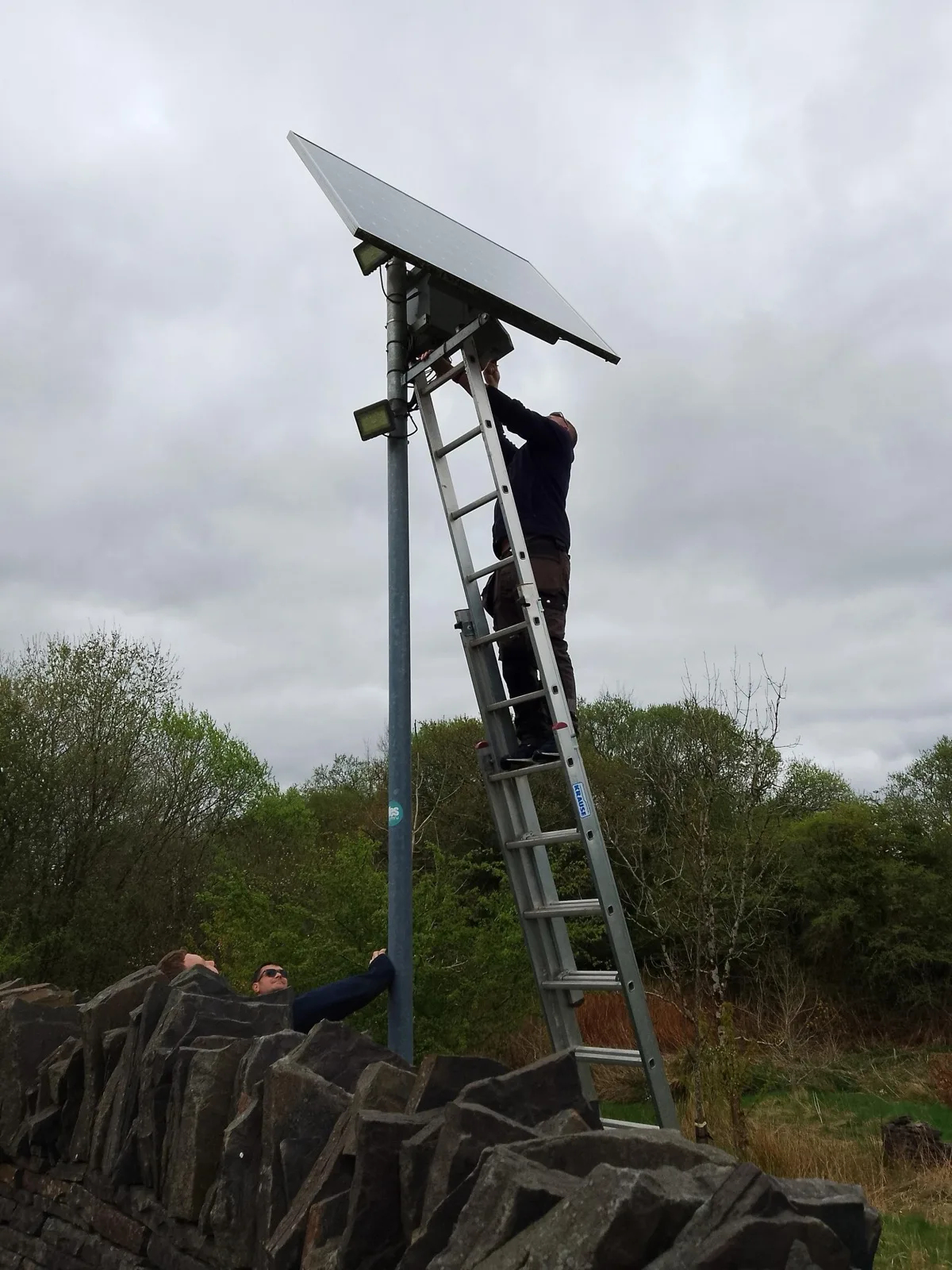 Blue Electrics engineer installing a standalone pole-mounted solar panel in rural South Wales